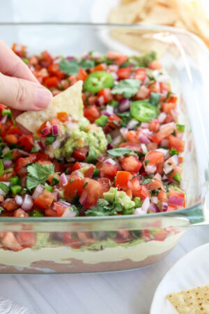 chip dipped into a dish of vegan 7 layer dip.