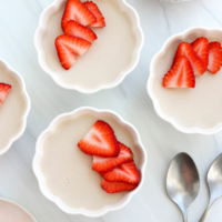 coconut panna cotta in bowls with strawberries on top.