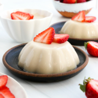 panna cotta served on a plate with strawberries.