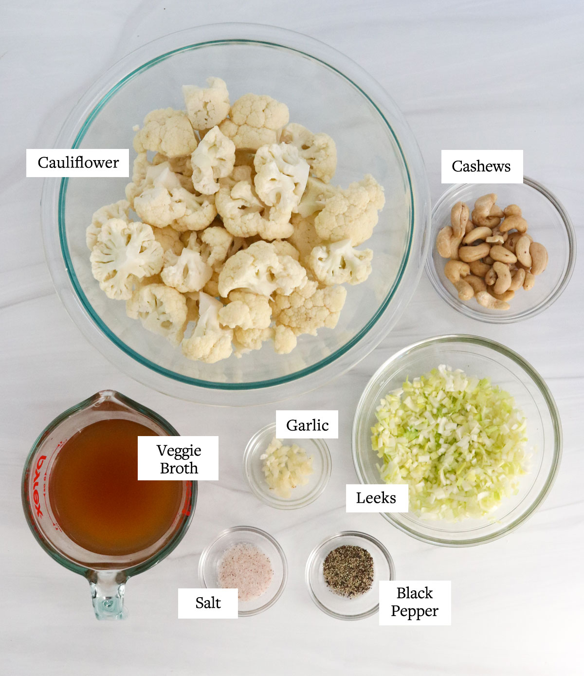 cauliflower ingredients in glass bowls on white surface