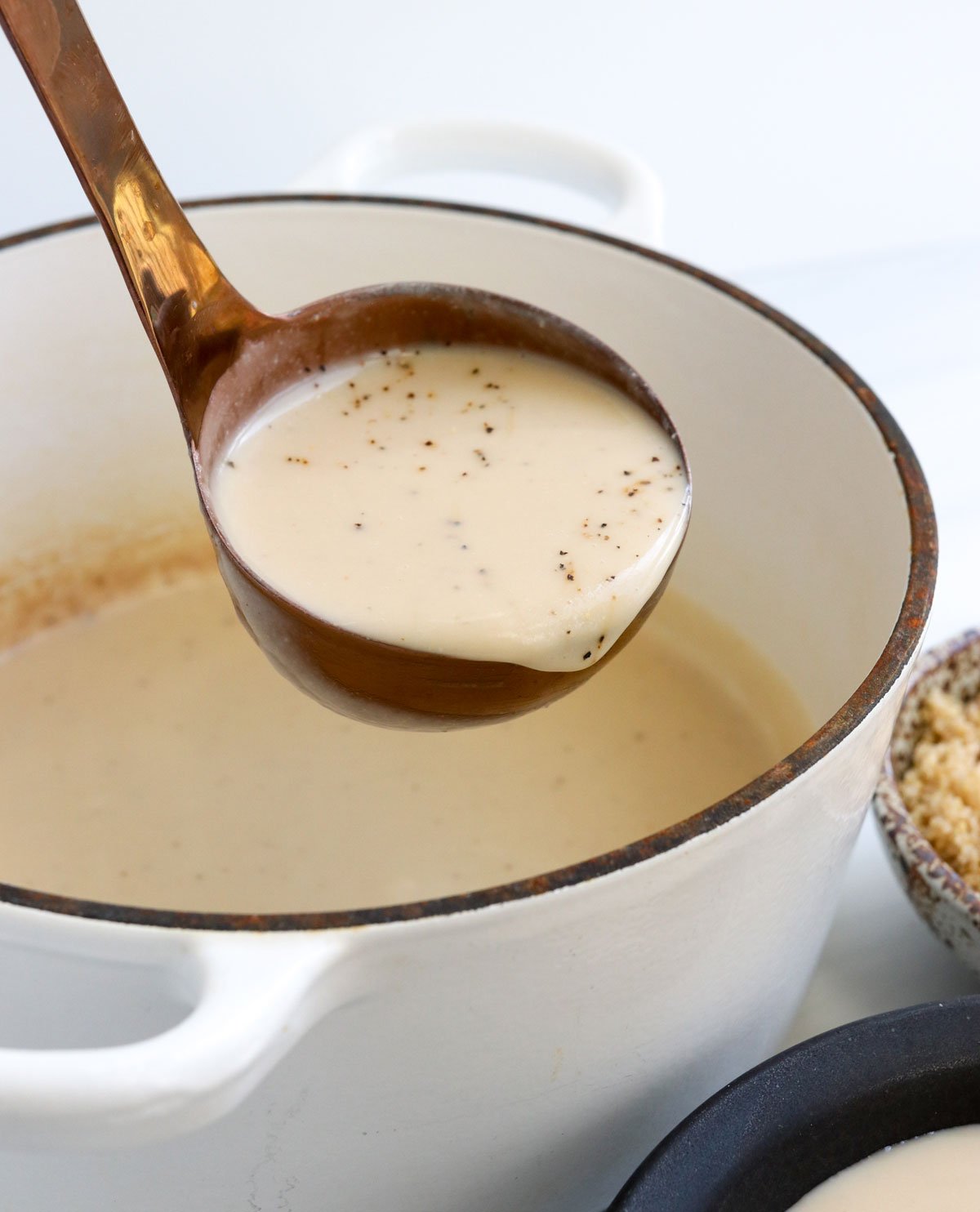 cauliflower soup on a ladle from a white pot