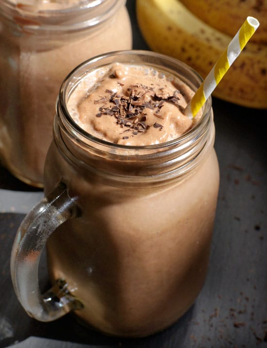 chocolate banana protein shake in a glass mug with chcocolate shavings on top