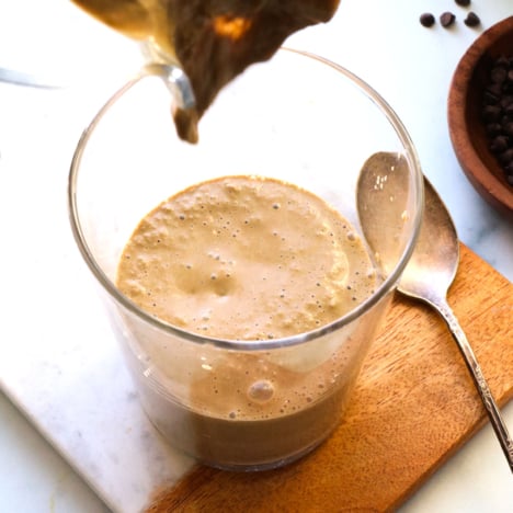 chocolate protein smoothie poured into a glass on a marble board.