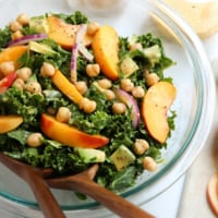 kale and peach salad with serving tongs