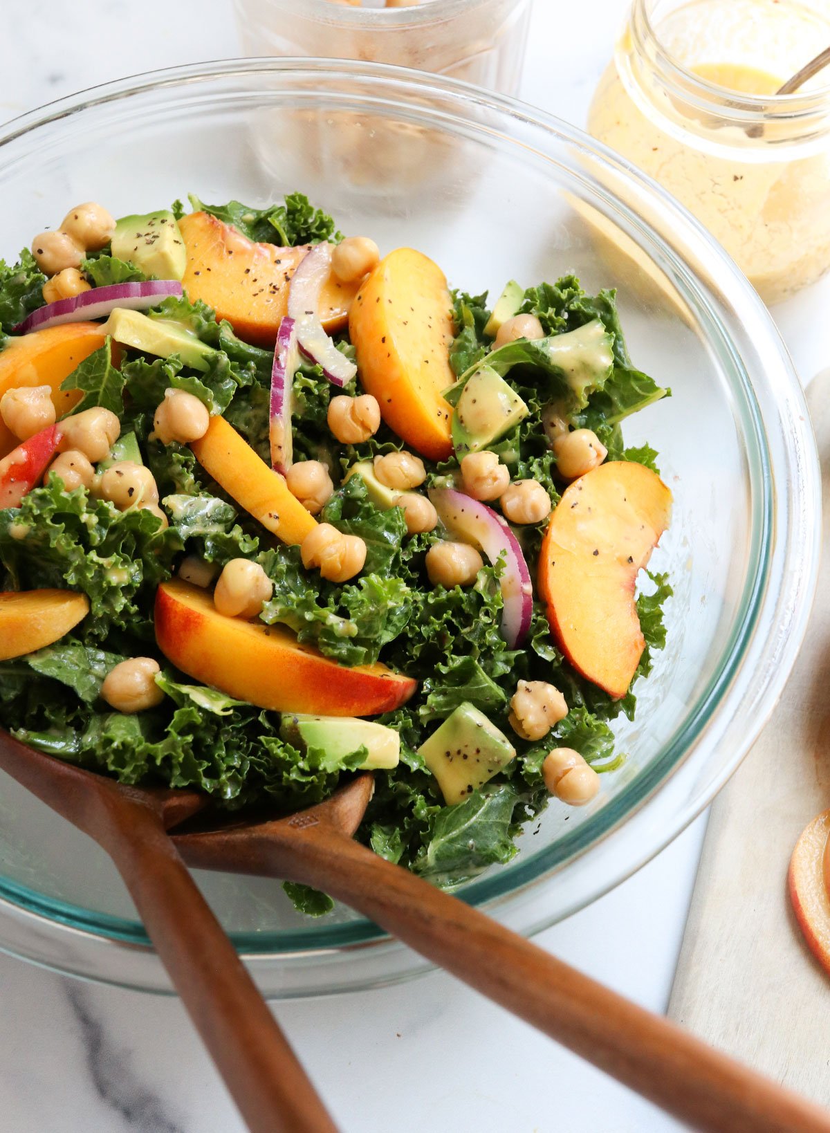 kale and peach salad with serving tongs