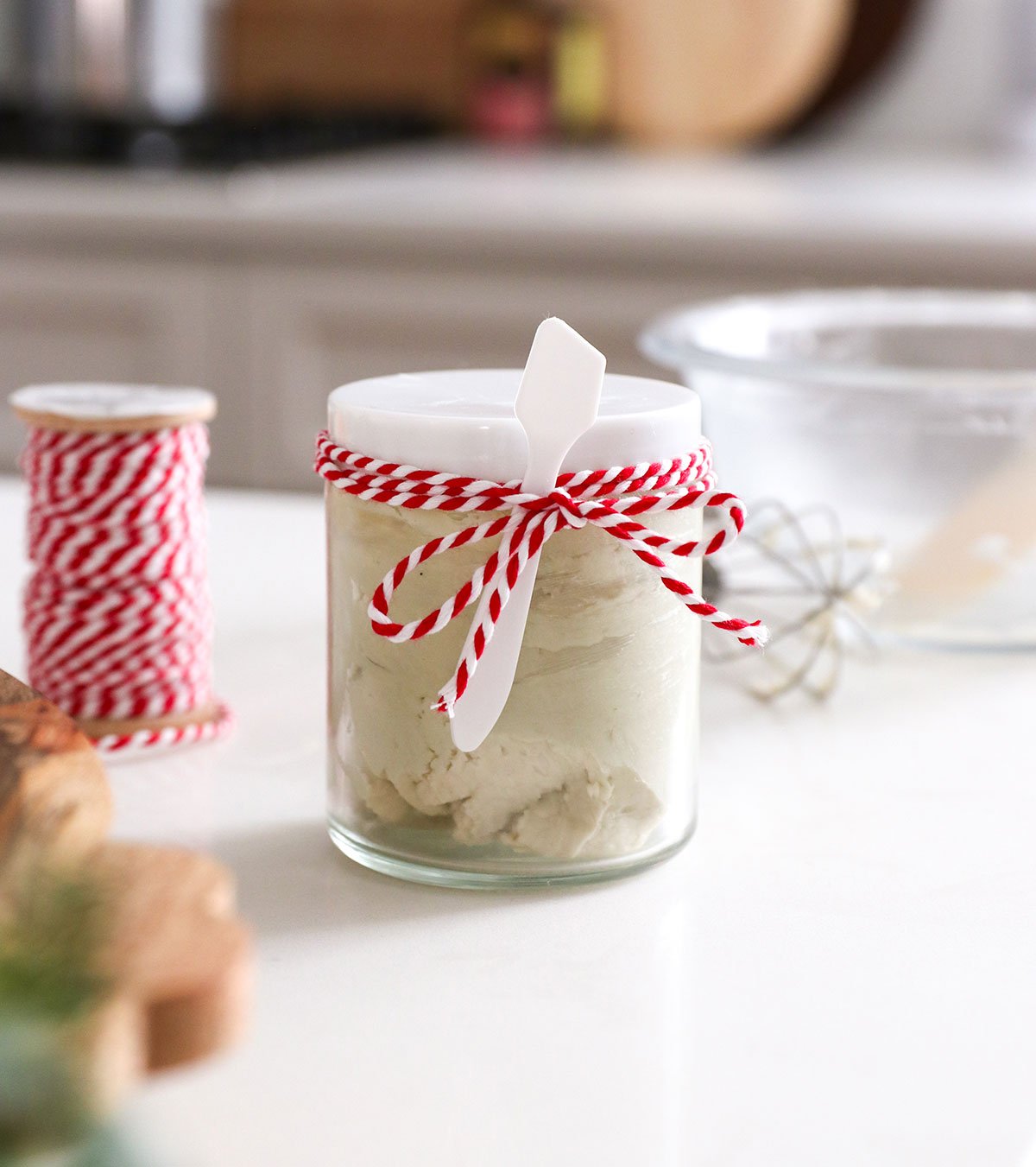body butter in a small glass jar with a bow.