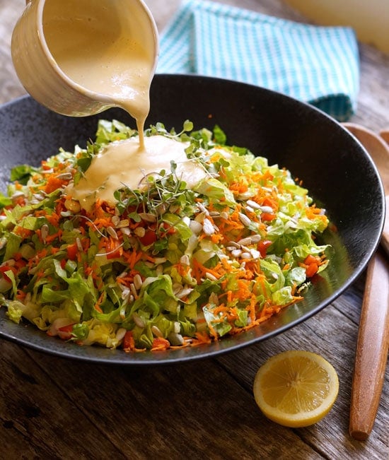 pouring creamy thai peanut dressing over a salad