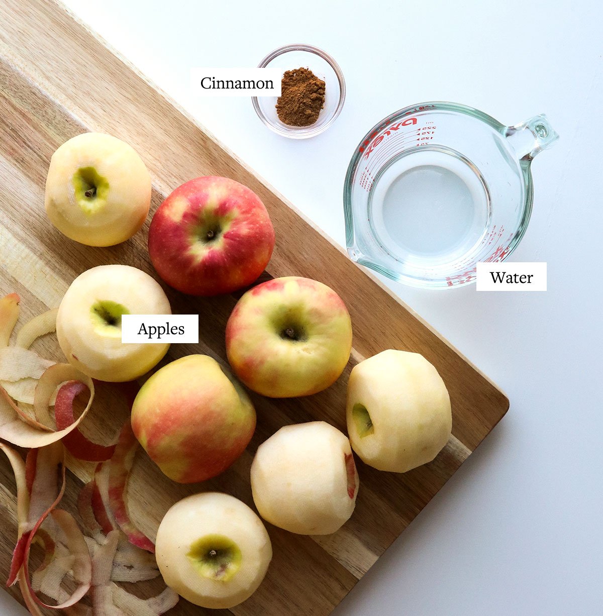 apples on cutting board with water and cinnamon labeled for making applesauce.