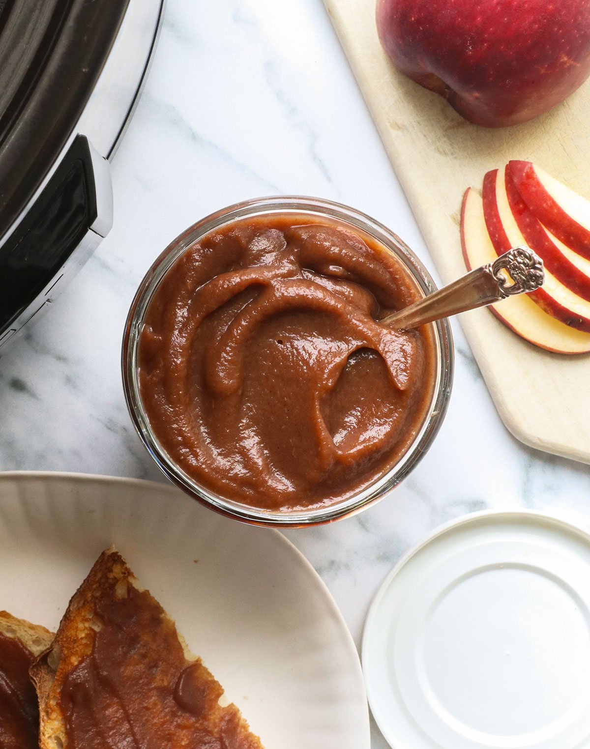 apple butter without added sugar in a glass jar with a spoon.