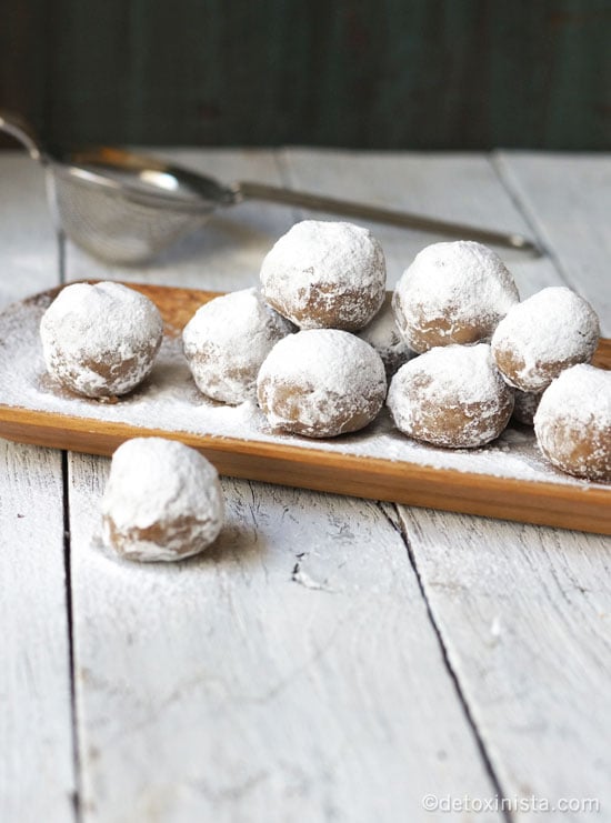 Photo shows a pile of pecan snowball cookies on a wood tray