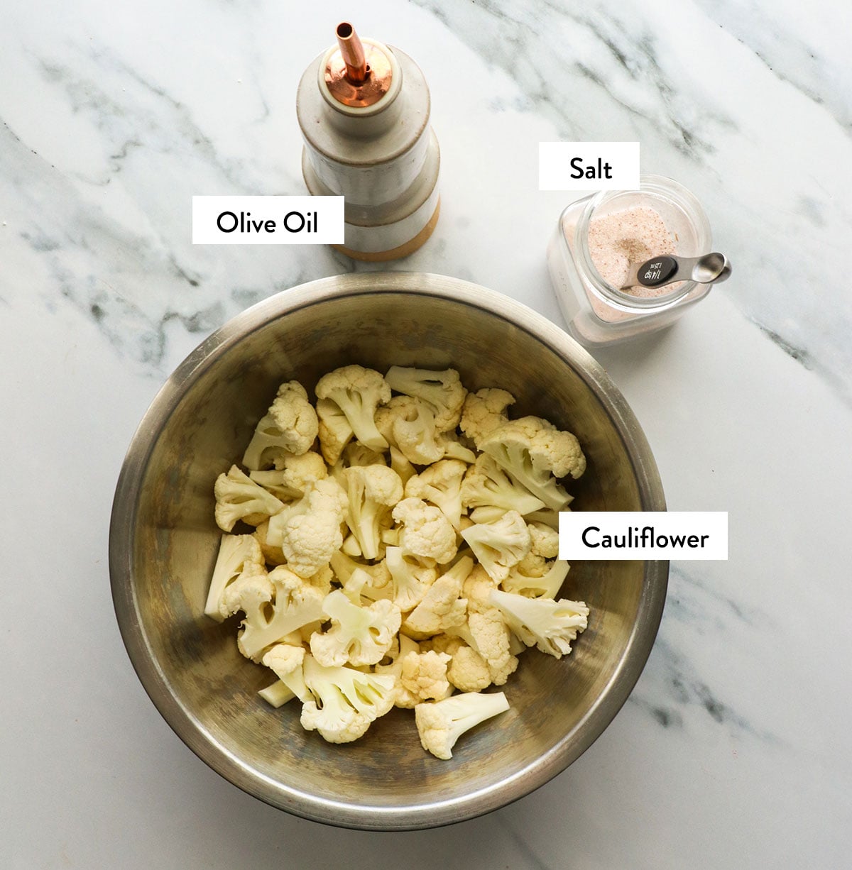 cauliflower in a bowl with olive oil and salt labeled.