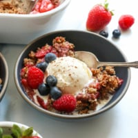 paleo berry crisp in dark bowl with ice cream