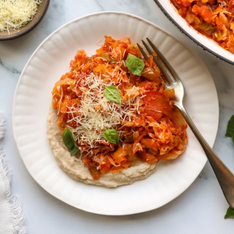pizza stir fry on white bean dip on a plate.