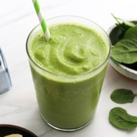 spinach smoothie in a glass with straw