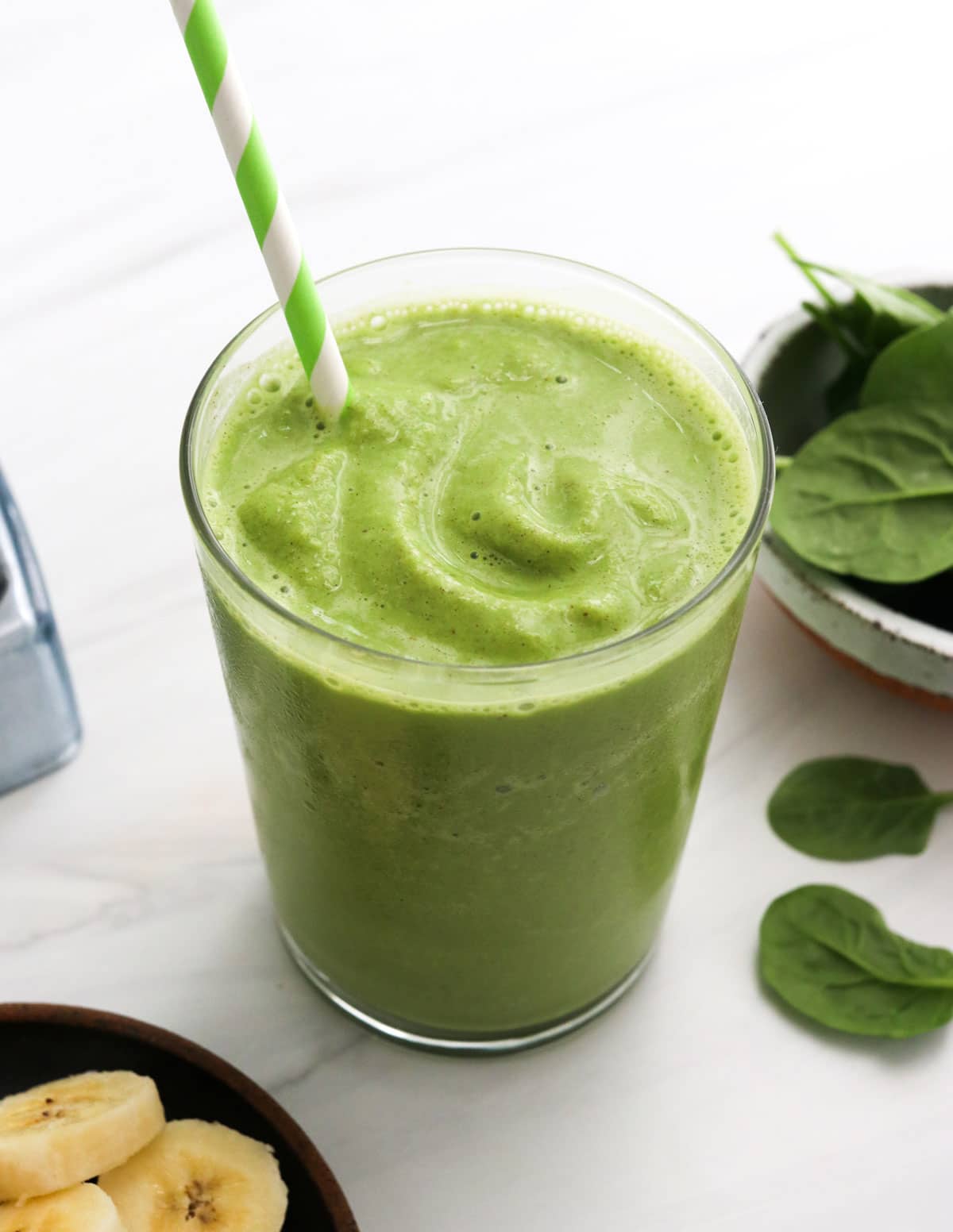 spinach smoothie in a glass with straw