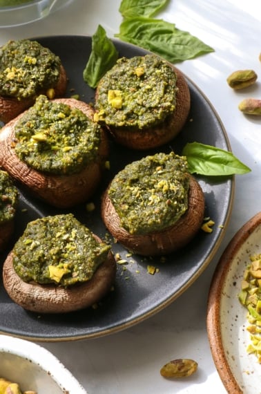 pesto mushrooms served on a dark plate.