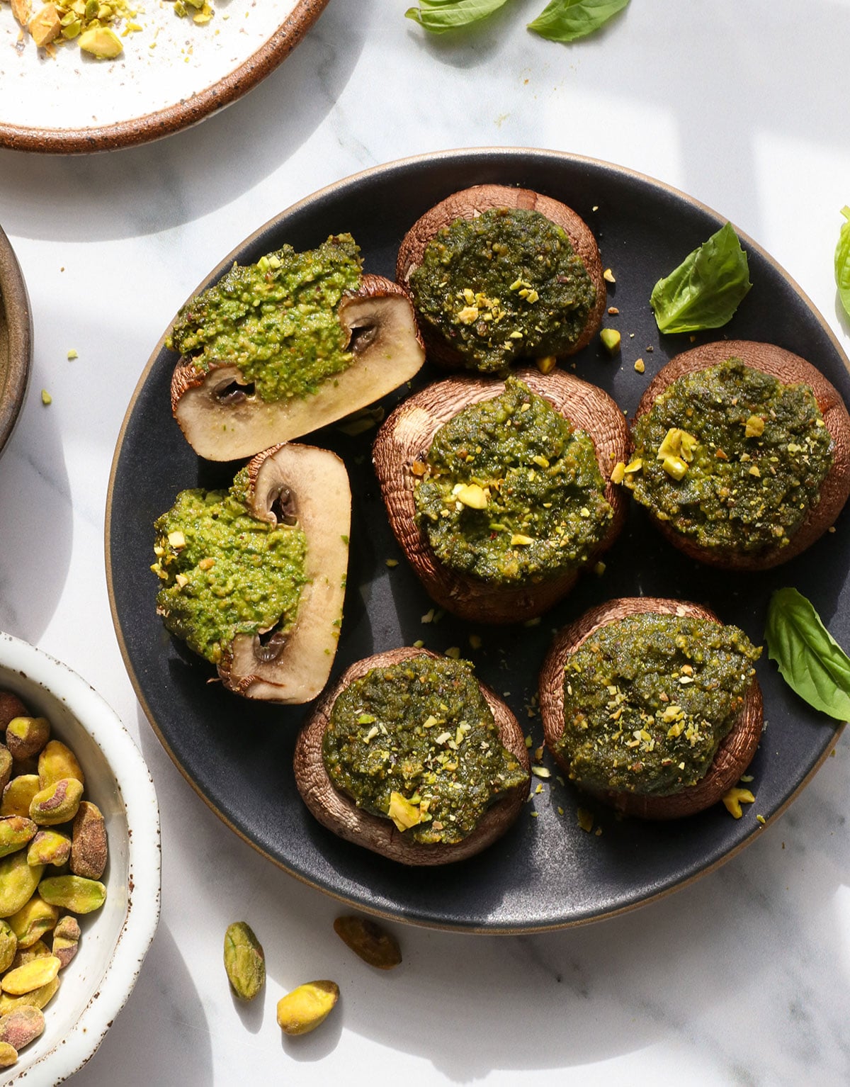 pesto mushrooms with one sliced in half on a dark serving plate.