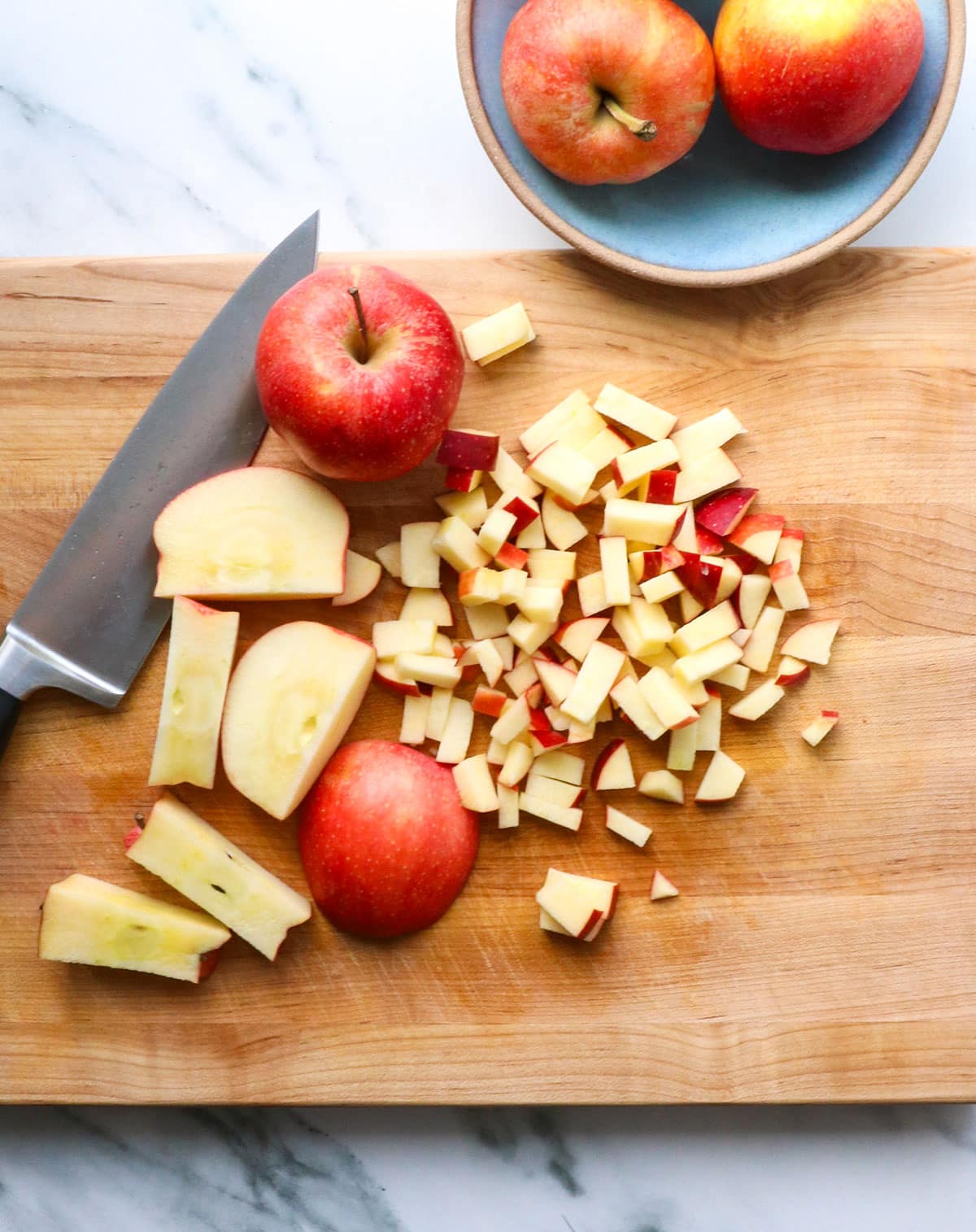 red apples cut into small chunks on a cutting board.