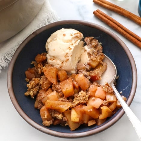 close up of paleo apple crisp with vanilla ice cream and a spoon.