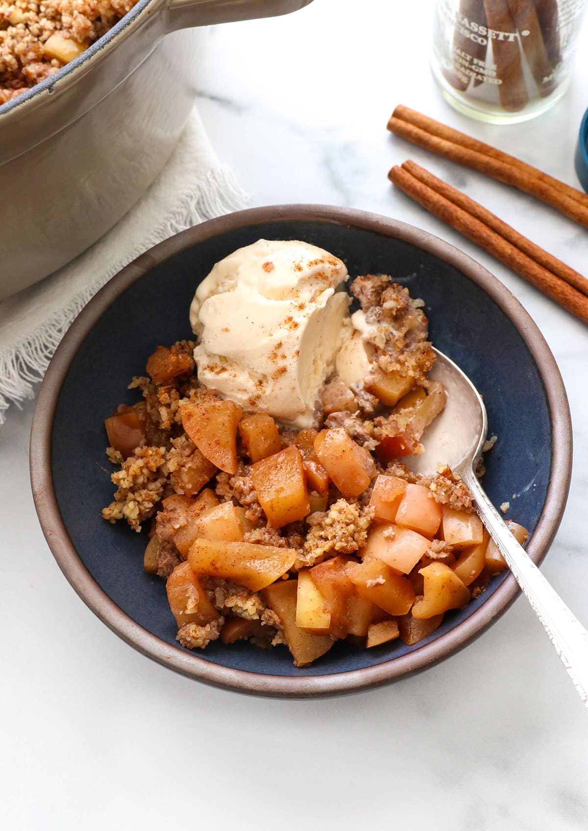 close up of paleo apple crisp with vanilla ice cream and a spoon.