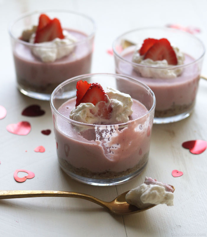 strawberry cream pies in small glass containers with whipped topping and strawberry slices on top