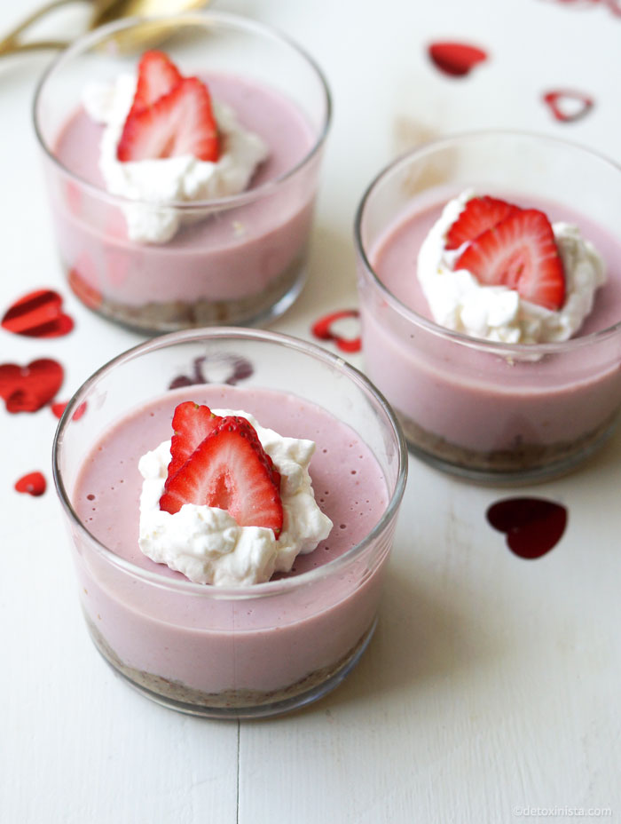 strawberry cream pies in small glass containers with whipped topiing and strawberry slices on top