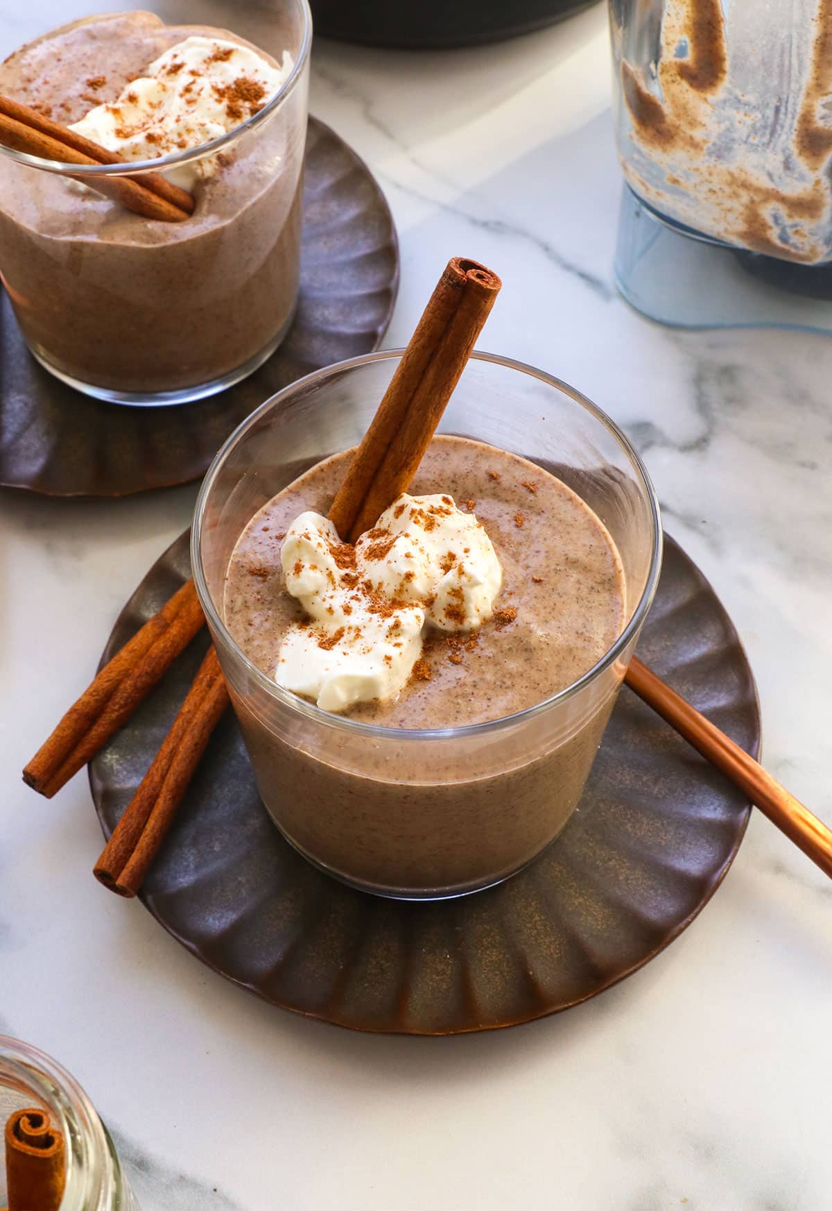 chai chia pudding topped with yogurt and cinnamon sticks.