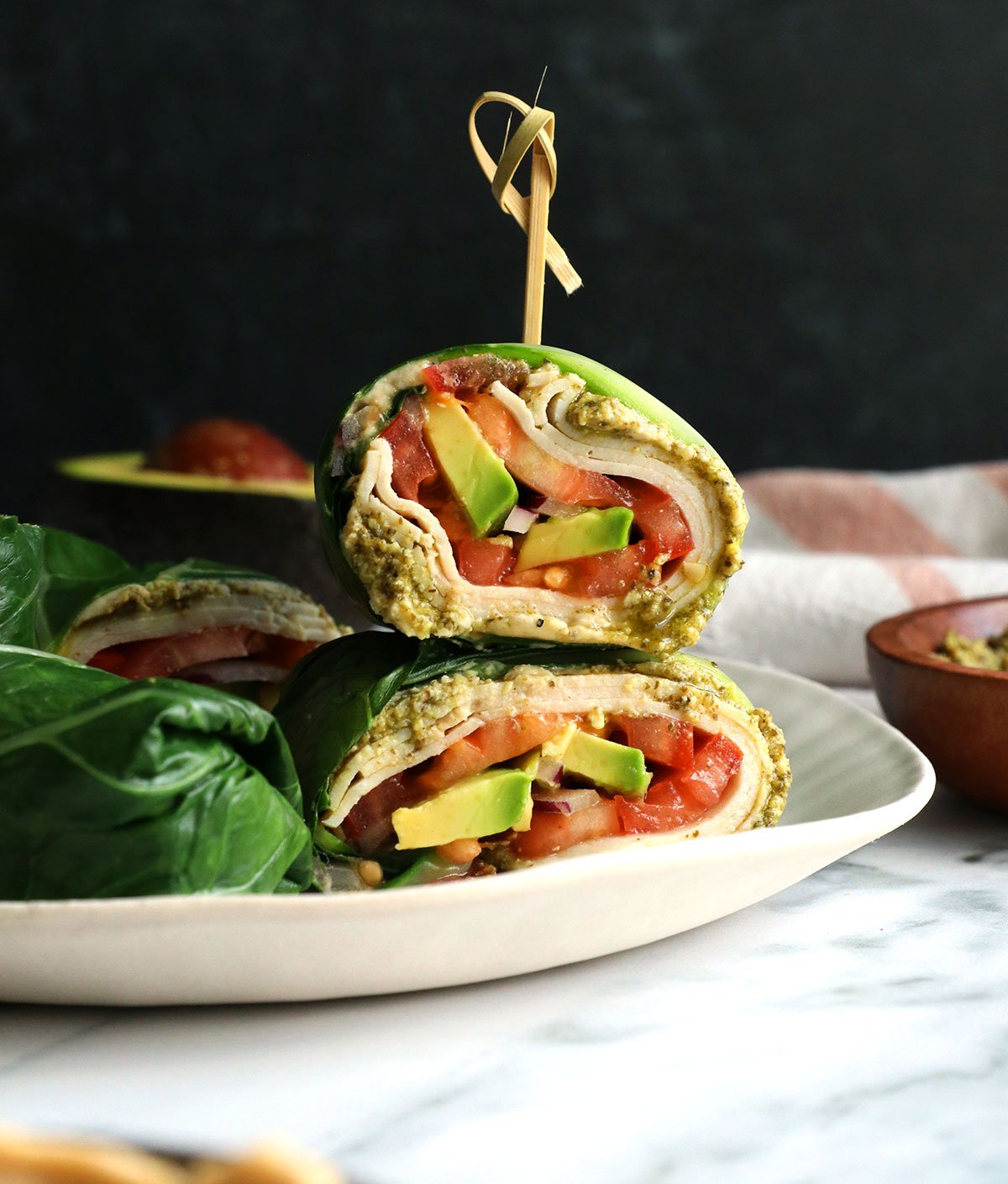 collard wraps stacked with a toothpick on a plate.