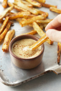 hand dipping french fry in vegan special sauce