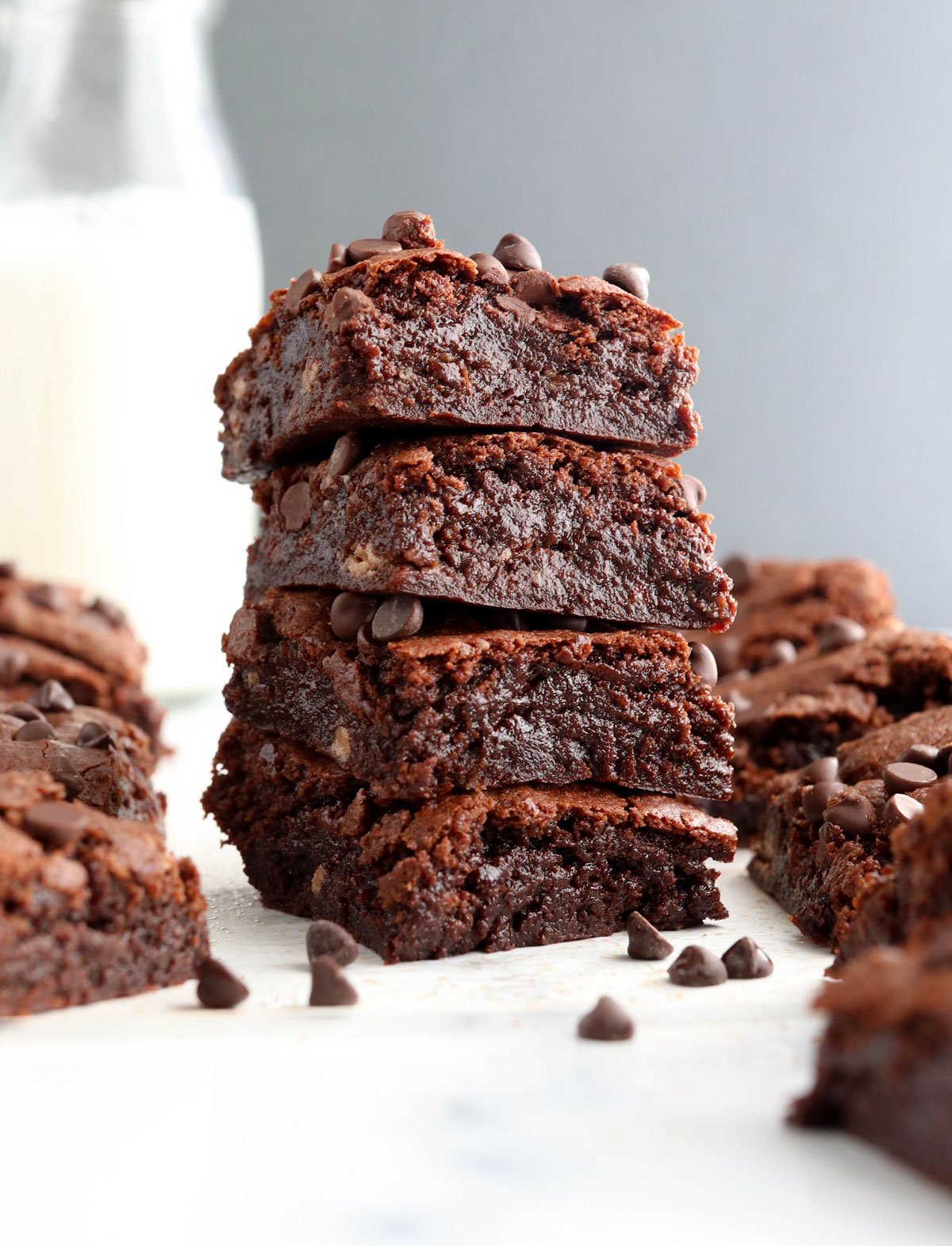 almond butter brownies stacked in front of a gray wall