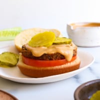 vegan burger sauce dripping off of a patty stacked on a bun.
