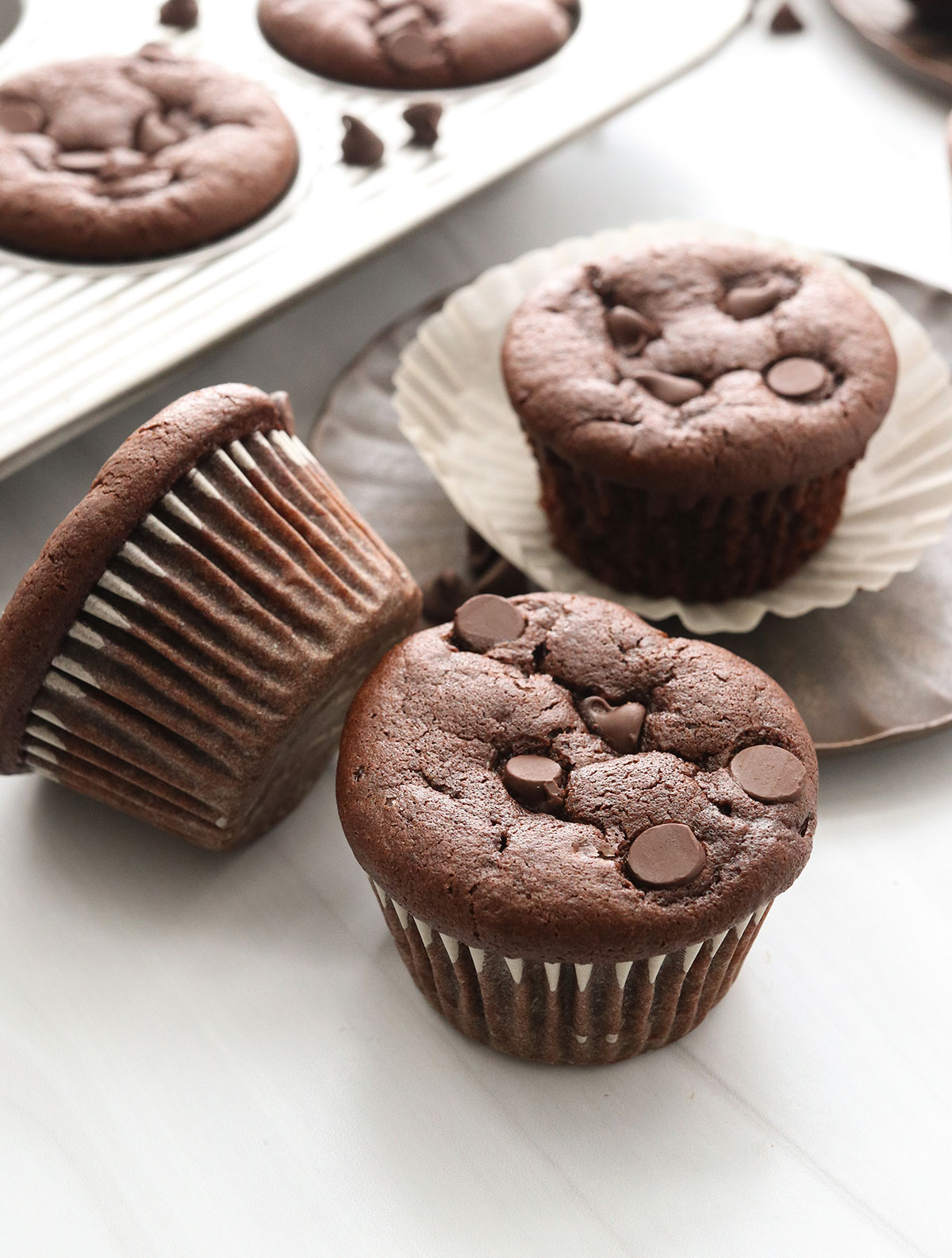 chocolate muffins sitting on a white counter.