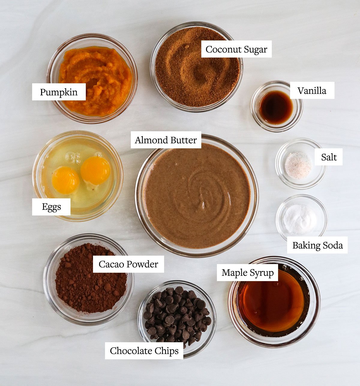 healthy chocolate muffin ingredients labeled in glass bowls.