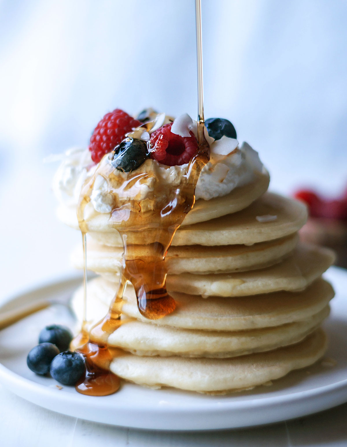 stacked pancakes with berries and syrup on top