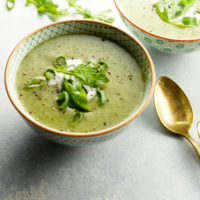 vegan arugula soup in bowl with gold spoon