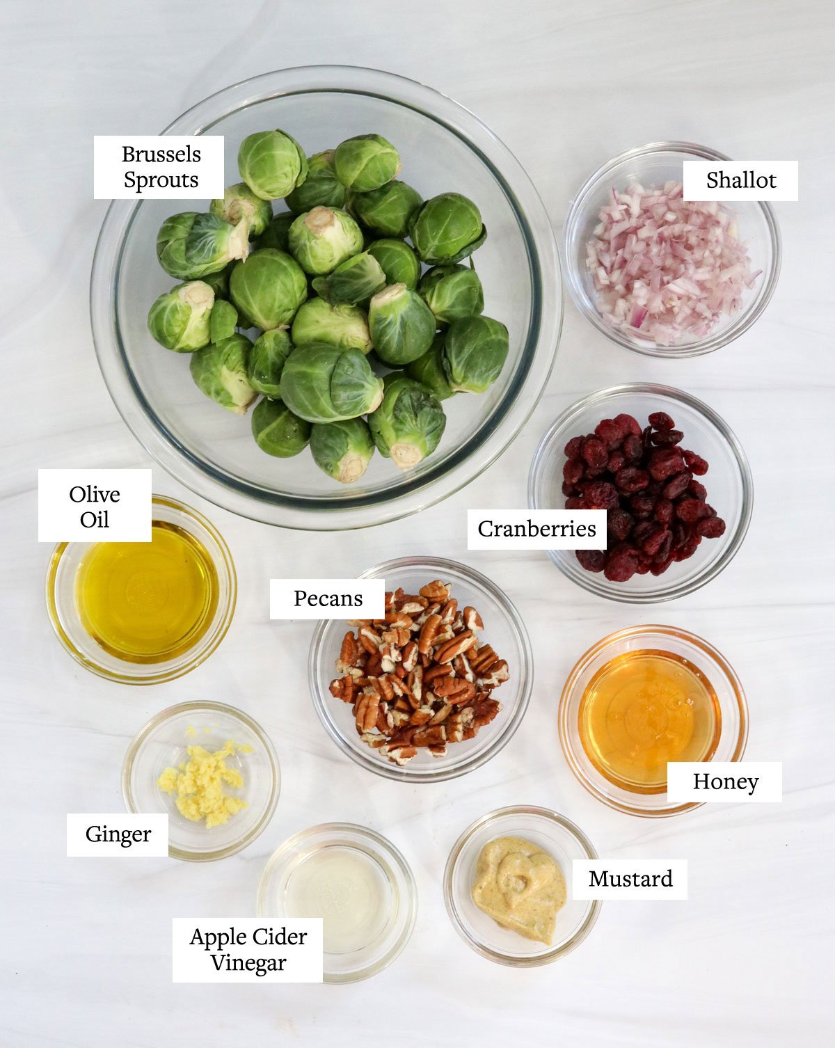 brussels sprouts salad ingredients in glass bowls on white table