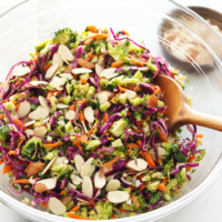 detox salad topped with sliced almonds in large glass bowl.