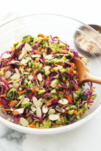 detox salad topped with sliced almonds in large glass bowl.