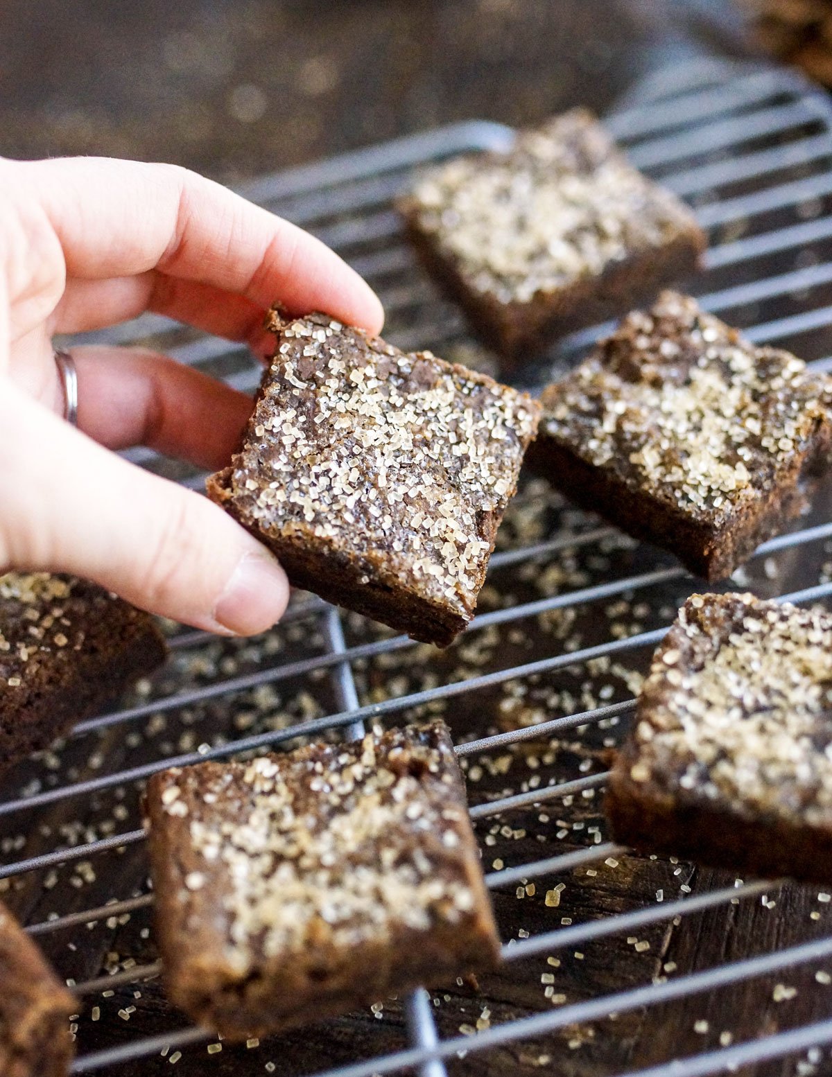 hand picking up a black bean gingerbread bar off of a cooling rack