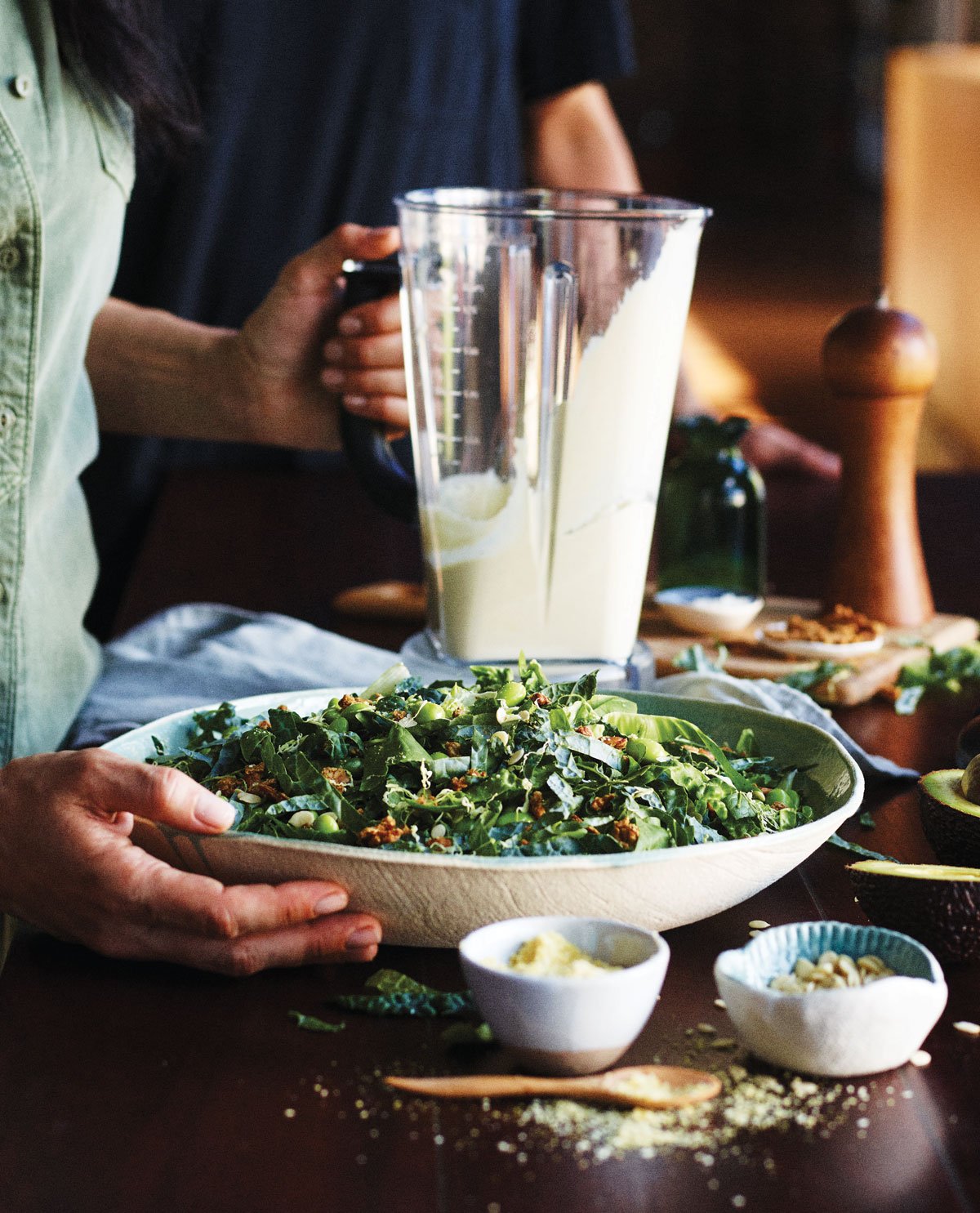 bowl of kale caesar salad with a blender full of dressing