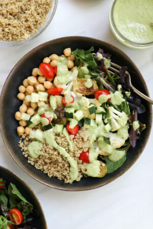 quinoa bowl topped with veggies and dressing.