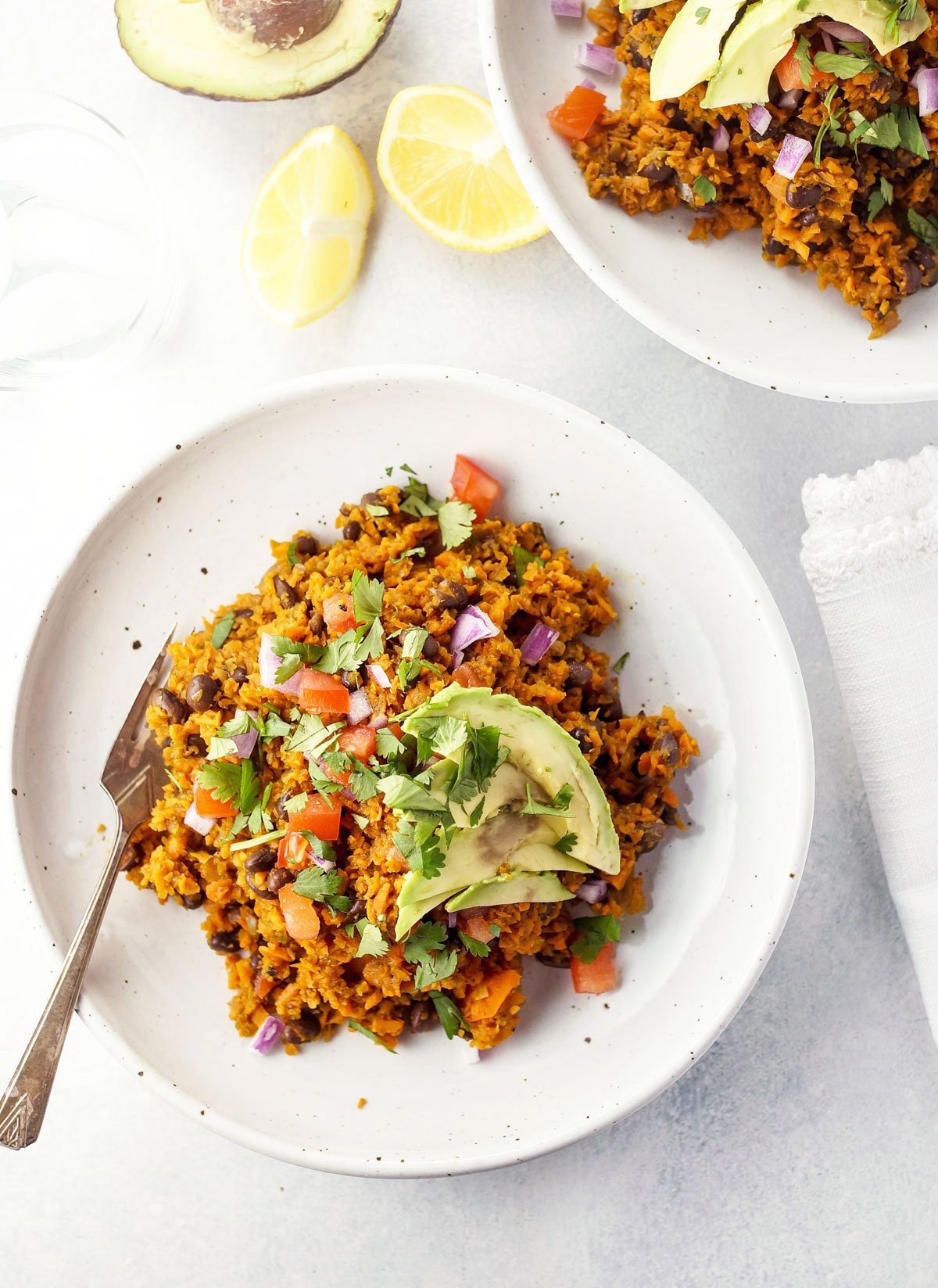 sweet potato burrito bowl on a plate with avocado on top