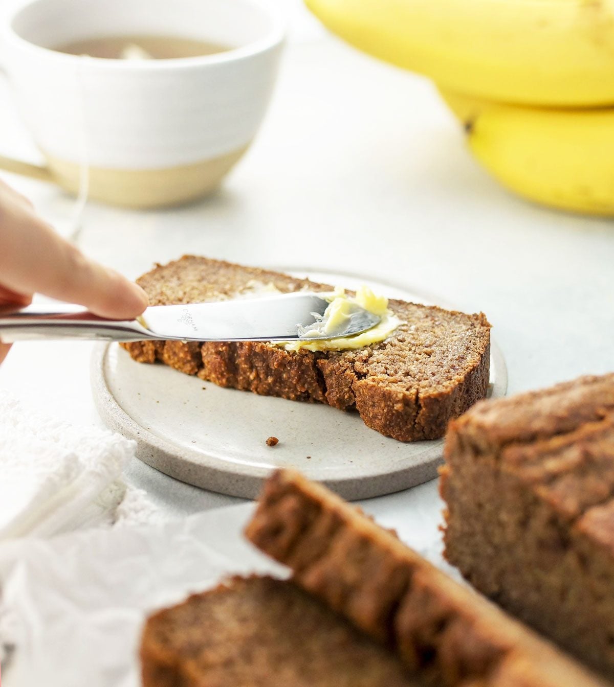 butter spread onto a slice of almond flour banana bread
