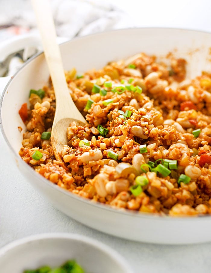 pan of Healthy Creole-Style Cauliflower Rice Jambalaya with a wooden spoon