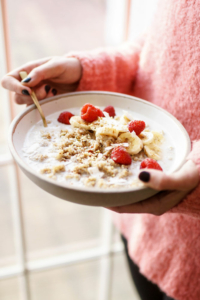 overhead quinoa breakfast bowl with raspberries held by woman