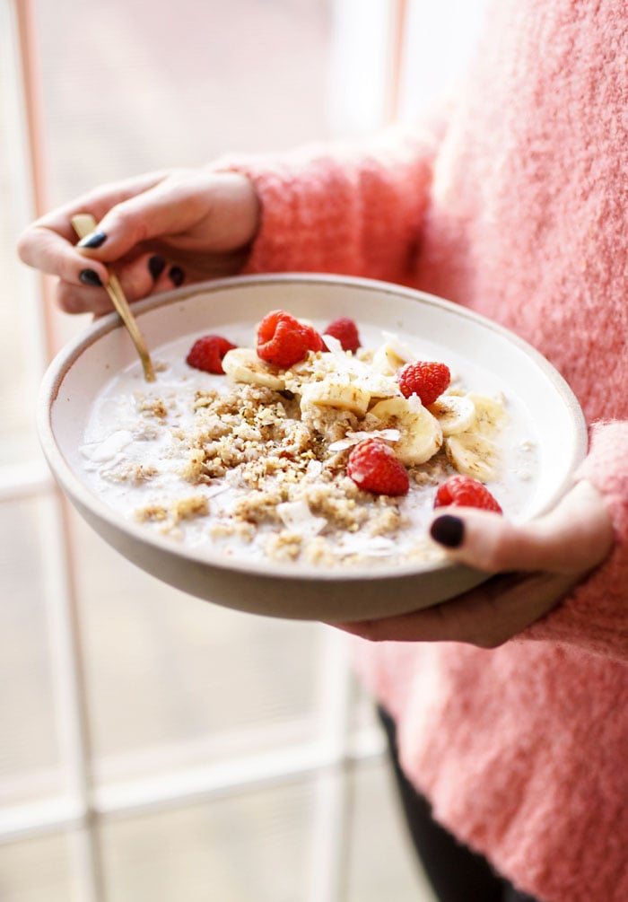 detox quinoa breakfast bowl with bananas and raspberries on top