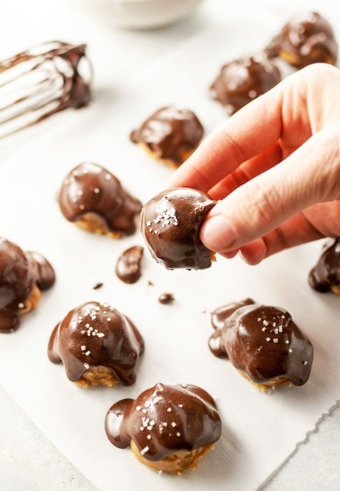 hand picking up almond butter buckeyes with chocolate and salt on top