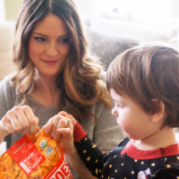 woman opening snack bag with toddler