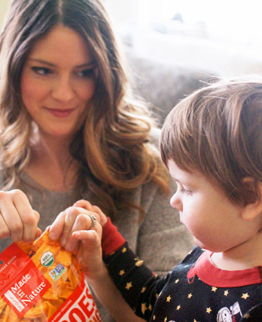 woman opening snack bag with toddler