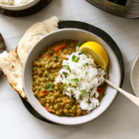 Instant Pot Lentil Curry served in a bowl with rice and lemon slices.